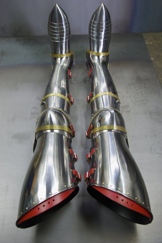 English style leg harness with fully closed cuisses, full greaves with characteristic line around outside ankles. Demi-greaves connected with greaves on rotary pin. Made of medium carbon steel of various thickness from 1 mm up to 1,5 mm. Heat hardened and tempered up to 42 HRC. Brass bands decoration motive based on example visible on Henry V tournament helm. Hand made steel buckles in set./Osony ng w stylu angielskim z w peni zamknitymi nabiodrkami, nagolennicami z charakterystyczn lini wok zewntrznej kostki. Demi-greave poczony z nagolennicami poprzez obrotowy pin. Wykonane ze stali redniowglowej rnej gruboci od 1 mm do 1,5 mm. Hartowane i odpuszczane do 42 HRC. Mosine listwy dekoracyjne z motywem wzorowanym na hemie turniejowym Henryka V. W zestawie rcznie robione sprzczki stalowe.